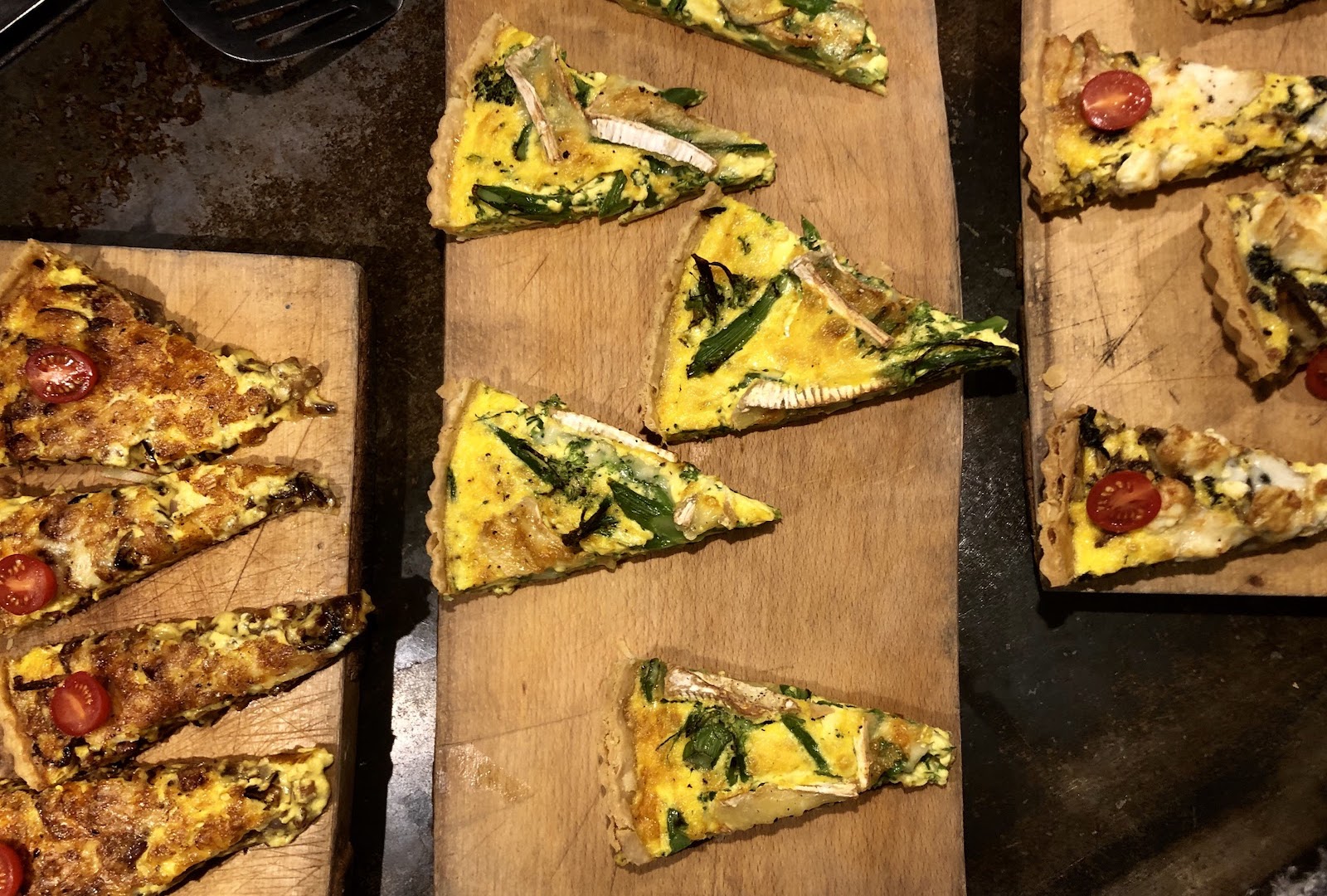 Three types of quiche laying on serving platters.